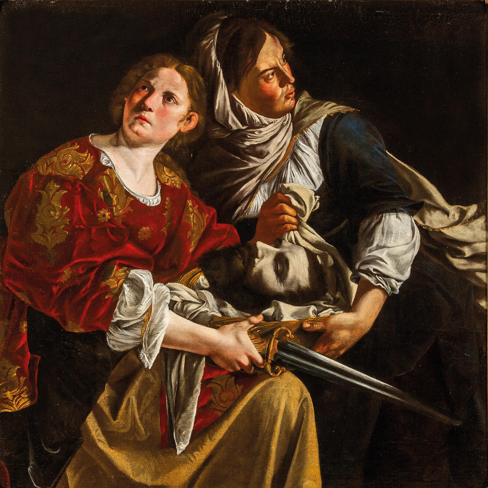 Giuditta e la sua serva con la testa di Oloferne: due figure illuminate emergono dall'oscurità; una tiene una spada, mentre la testa di Oloferne è avvolta in un drappo.